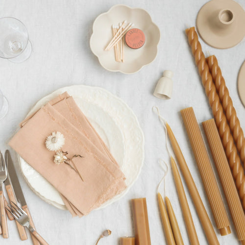 White flower shaped ceramic candle snuffer about to extinguish the flame on a taper candle