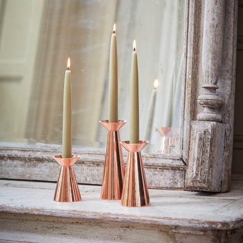 Our copper grand taper holders offer a modern take on a classic object, instantly elevating any setting. The luminous copper finish reflects light and lends a sense of movement to a table or mantlepiece, especially when paired or gathered as a trio. Each copper plated holder is sized to fit a standard taper candle.