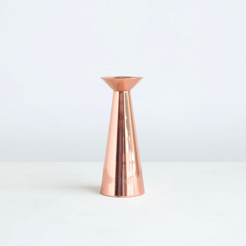 Our copper grand taper holders offer a modern take on a classic object, instantly elevating any setting. The luminous copper finish reflects light and lends a sense of movement to a table or mantlepiece, especially when paired or gathered as a trio. Each copper plated holder is sized to fit a standard taper candle.